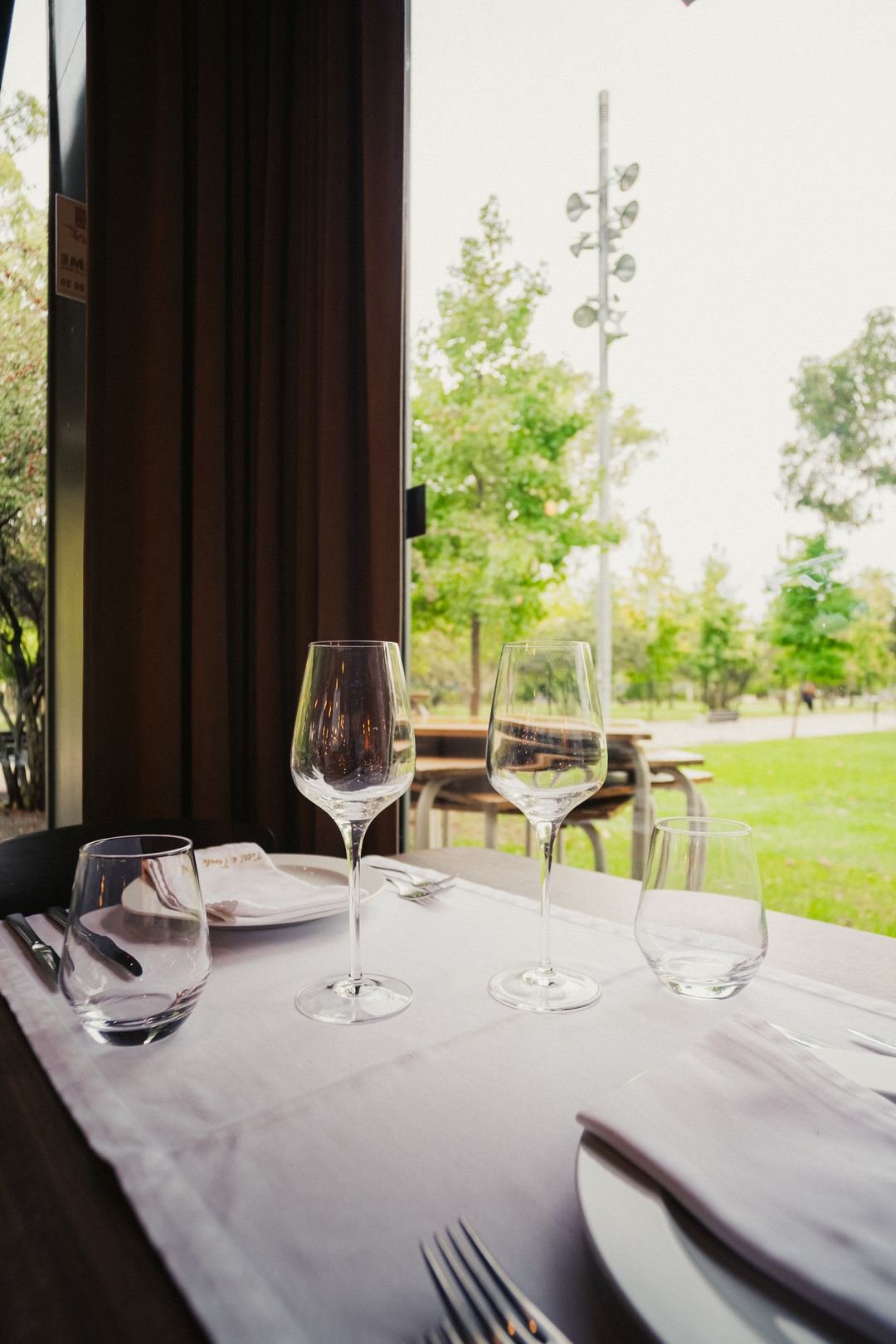 Uma mesa posta junto à janela, com o jardim lá fora