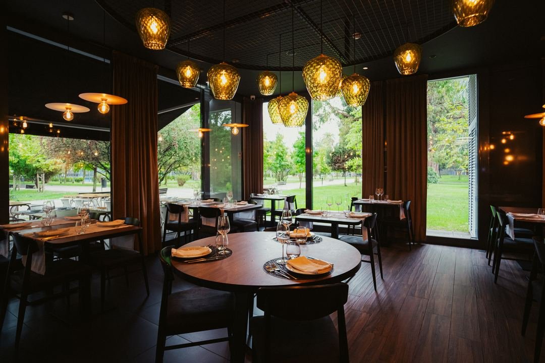 A sala com candeeiros de vidro âmbar e janelas largas para o jardim